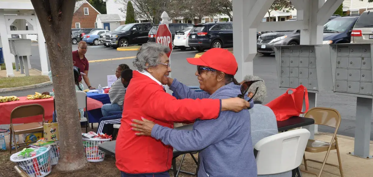 Two elders of color sharing a joyful embrace.