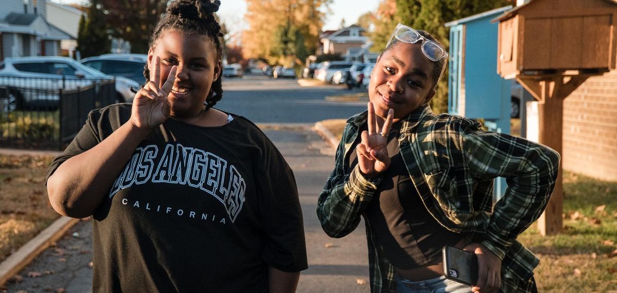 Two young girls giving peace sign to camera