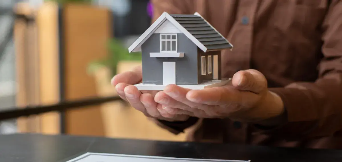 Hands holding a scale model of a house