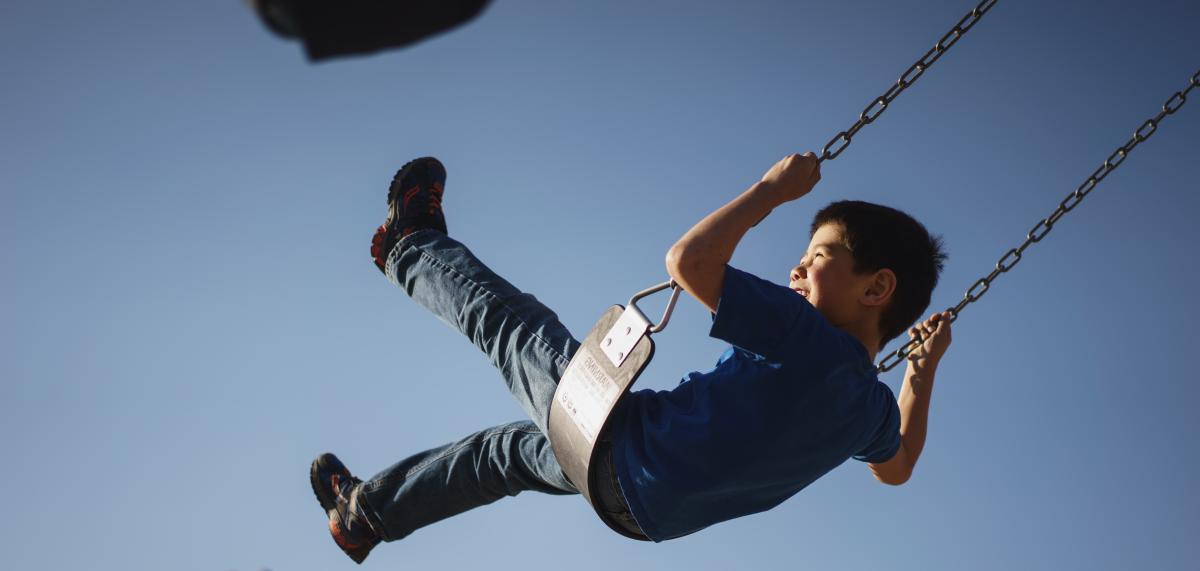 Child on a swing on a playground, swinging high