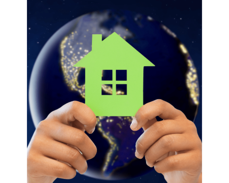 Hands holding house cutout with earth in background