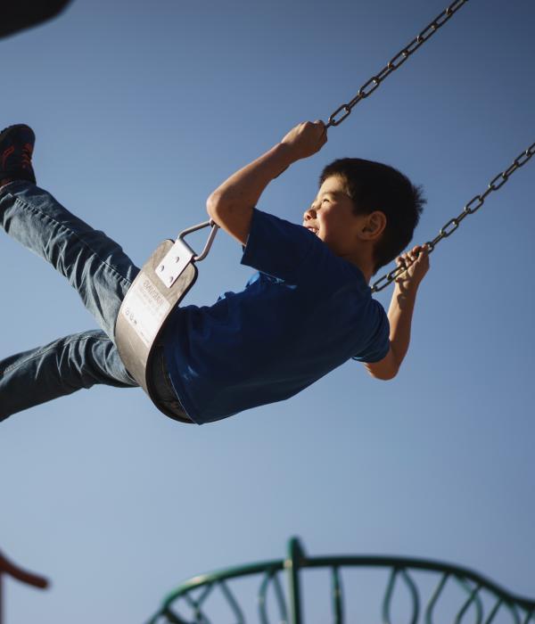 Child on a swing on a playground, swinging high