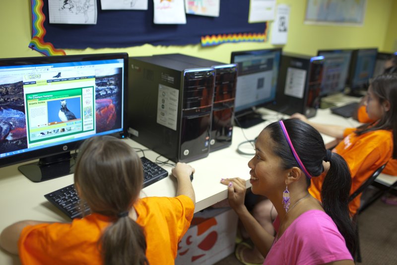 Community member demonstrates computer usage to young resident